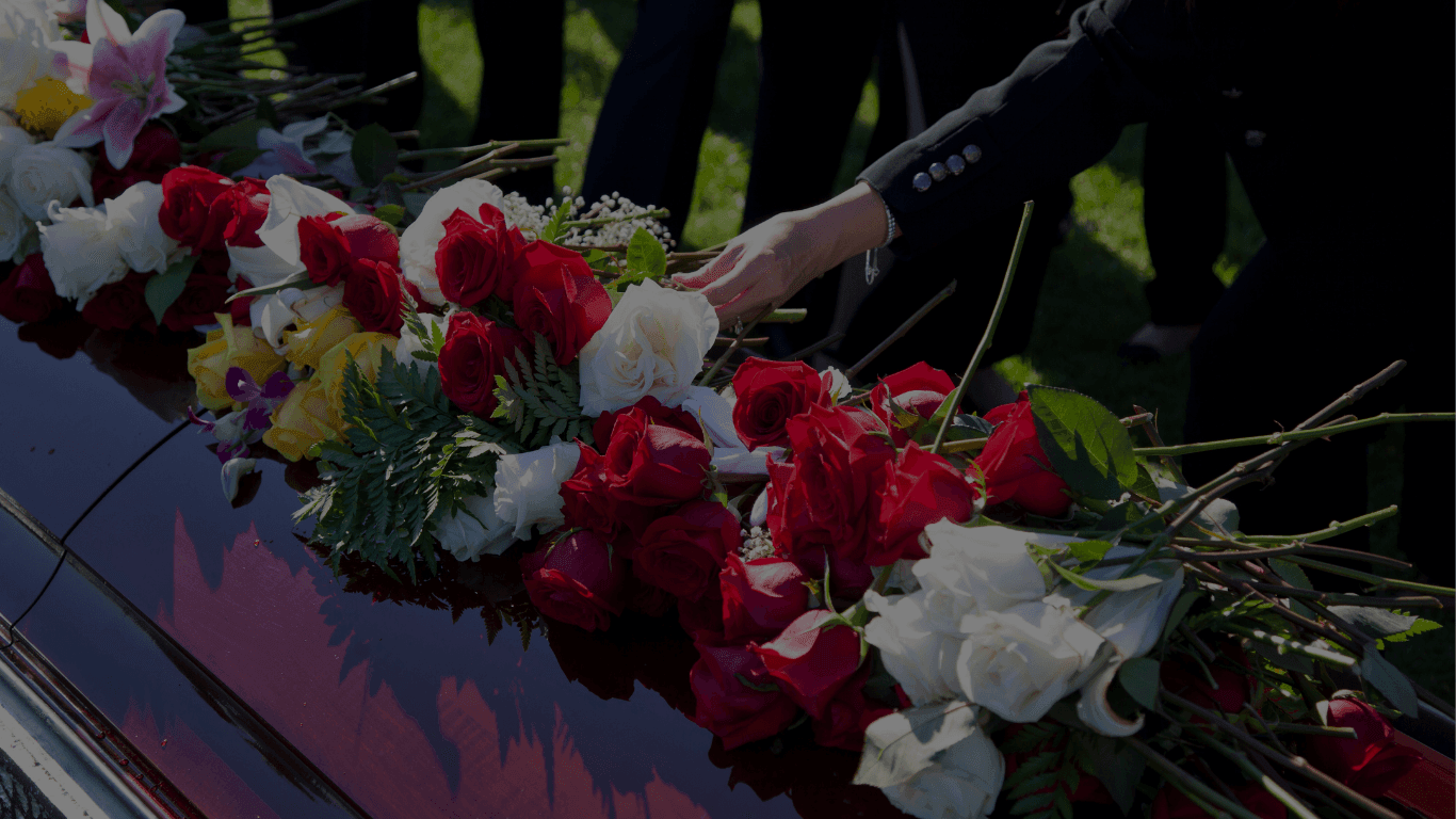 REM Legacy Foundation - How We Help: Family member at a funeral putting flowers on the casket