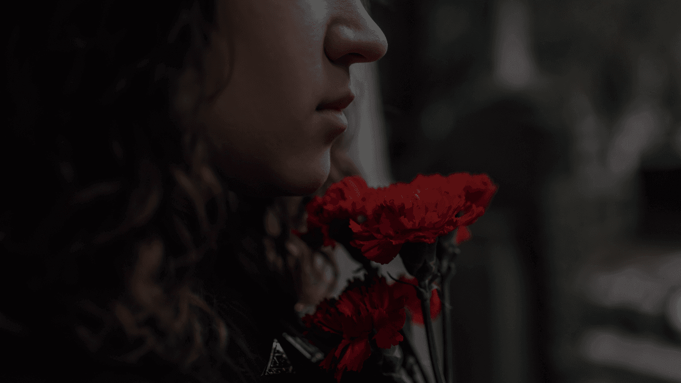 REM Legacy Foundation - Who We Help: Image of a grieving woman with a red flower